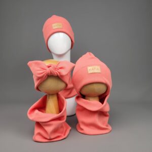 Koralowa czapka prążkowana z naszywką Katia na manekinie, obok komin i opaska z kokardą w tym samym kolorze