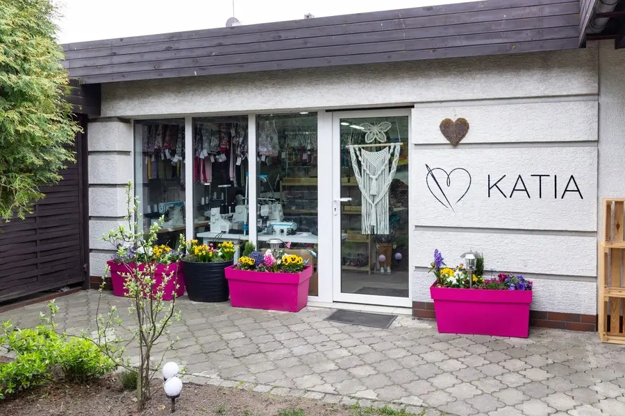 Wejście do pracowni Katia w Święciechowie: witryna z logo marki i donice z kwiatami